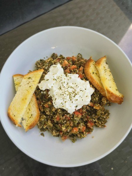 Sauteed seasoned greens with diced peppers, topped with cream and toasted garlic bread