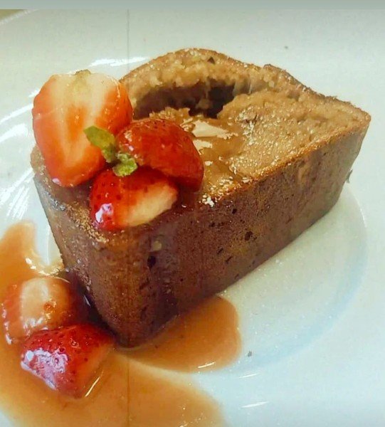 Warm cake slice with strawberries and syrup